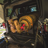 Outdoor lifestyle image of Big Timber Pro 20 degree sleeping bag, olive green color, rolled up and packed in the back of a jeep.