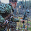 SJK Pursuit Hunting Vest in Kryptek Highlander camouflage on a male hunter holding a bow while crouched.