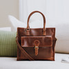 brown leather tote bag with large front pocket, carry handles and long adjustable shoulder strap