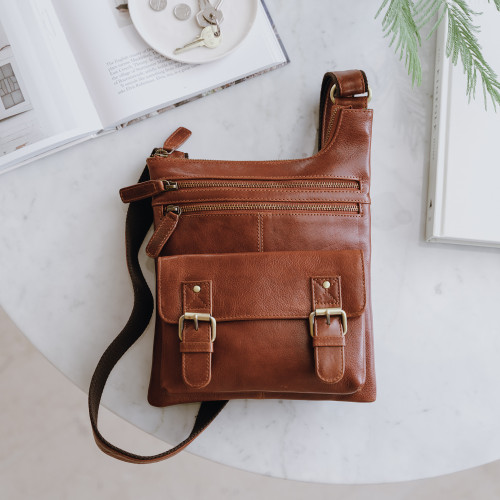 small tan leather crossbody bag with front pockets and long adjustable shoulder strap