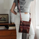 small brown leather crossbody bag with front pockets worn on a model