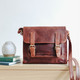 brown oiled leather satchel with buckle fastening and long shoulder strap