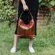 tan leather hobo tote with handle being held by model