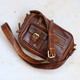 tan vegetable tanned leather handbag with front pockets and long shoulder strap