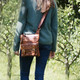small tan leather crossbody bag with front pockets worn on a model