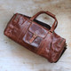 brown large leather travel bag with pockets and long crossbody strap