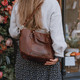 brown leather grab bag with two handles and detachable crossbody strap, worn on models shoulder