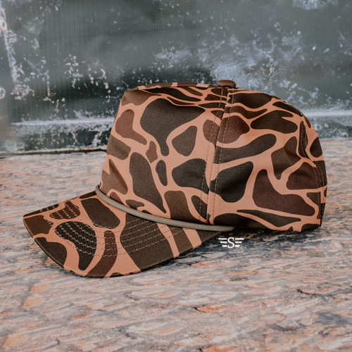 duck camo cap, brown duck camo hat, western camo baseball cap, camouflage hat for women, neutral camo cap, brown camouflage hat, western street style cap, boutique camo hat, everyday camo baseball cap, modern duck camo hat, outdoor lifestyle cap, western camo fashion hat, casual camo hat, hunting inspired camo cap, ranch style camo hat, farm life hat, country lifestyle cap, neutral brown camo hat, women’s camo baseball cap, snapback camo hat, structured camo cap, western boutique cap, camo hat with rope detail, rope hat western style, classic rope baseball cap, brown and tan camo hat, minimalist camo hat, understated camouflage cap, unisex camo baseball cap, outdoorsy lifestyle hat, western mom hat, practical everyday cap, durable camo hat, camo hat for ranch wear, camo hat for casual outfits, camo hat for travel, neutral tone camo hat, modern western camo cap, Flying S style cap, boutique western camo accessory