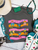 Bright, bold, and full of western spirit, our Life of a Cowboy Vibrant Graphic Tee celebrates the grit, tradition, and excitement of cowboy life. Featuring colorful hand-drawn rodeo scenes—including bronc riding, roping, ranch work, fencing, and western tack—this eye-catching design is finished with playful retro-inspired stripes that make it a true statement piece.
Printed on your choice of Softstyle, Comfort Colors, or a Muscle Tank, this tee is incredibly soft and perfect for rodeos, county fairs, livestock shows, country concerts, or everyday western style. Whether you grew up in the arena or simply love the western way of life, this shirt brings cowboy culture to life with a fun, artistic twist.