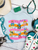 Bright, bold, and full of western spirit, our Life of a Cowboy Vibrant Graphic Tee celebrates the grit, tradition, and excitement of cowboy life. Featuring colorful hand-drawn rodeo scenes—including bronc riding, roping, ranch work, fencing, and western tack—this eye-catching design is finished with playful retro-inspired stripes that make it a true statement piece.
Printed on your choice of Softstyle, Comfort Colors, or a Muscle Tank, this tee is incredibly soft and perfect for rodeos, county fairs, livestock shows, country concerts, or everyday western style. Whether you grew up in the arena or simply love the western way of life, this shirt brings cowboy culture to life with a fun, artistic twist.