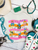 Bright, bold, and full of western spirit, our Life of a Cowboy Vibrant Graphic Tee celebrates the grit, tradition, and excitement of cowboy life. Featuring colorful hand-drawn rodeo scenes—including bronc riding, roping, ranch work, fencing, and western tack—this eye-catching design is finished with playful retro-inspired stripes that make it a true statement piece.
Printed on your choice of Softstyle, Comfort Colors, or a Muscle Tank, this tee is incredibly soft and perfect for rodeos, county fairs, livestock shows, country concerts, or everyday western style. Whether you grew up in the arena or simply love the western way of life, this shirt brings cowboy culture to life with a fun, artistic twist.