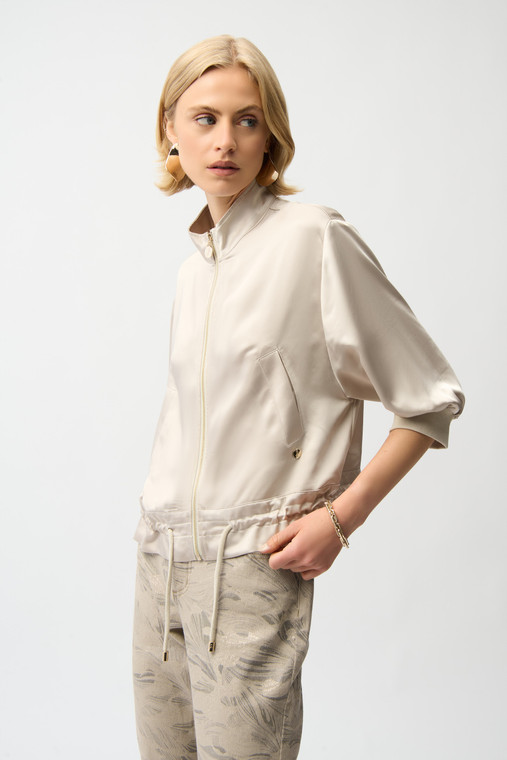 This satin boxy blouson jacket features a funnel neck collar, drop shoulder three-quarter sleeves with ribbed cuffs, and a drawstring hem.
