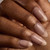 Close-up of almond-shaped nude builder gel nails on a hand, featuring a sheer pink-beige overlay with a natural glossy finish