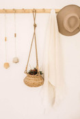 Circular rattan basket hanging from three jute ropes