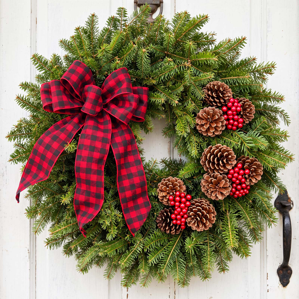 Buffalo Plaid fresh Maine balsam Christmas wreath with pinecones, red berries and red-and-black plaid bow on a white wooden door