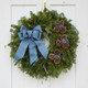 Front view of the Bar Harbor fresh Maine balsam wreath with a blue linen bow and blueberries centered on a white rustic door.