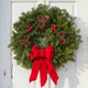 The original 1986 Downeaster fresh Maine balsam wreath featuring a red velvet bow at the bottom and large berry clusters on a white door.