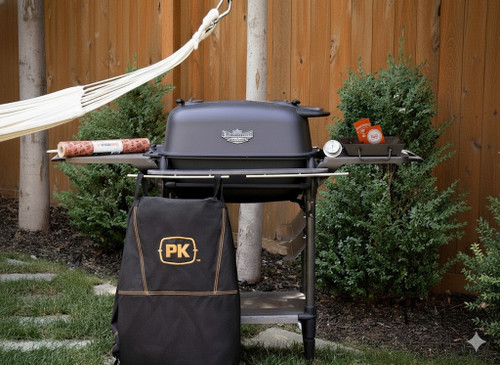 PK Grills PK300AF Start Cookin' Bundle - Coal, outdoor barbecue grill with accessories set up in a backyard with a wooden fence and greenery.