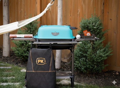 PK Grills PK300AF Start Cookin' Bundle - Teal, outdoor BBQ grill with teal lid, side tray, and black PK logo bag in a garden setting.