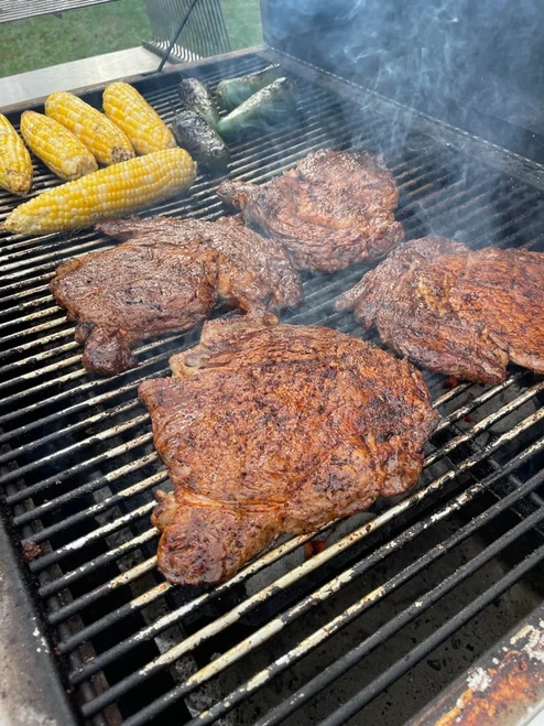 Hardcore Carnivore: Tex Mex seasoning, grilled steaks and corn on the cob cooking on a barbecue grill.