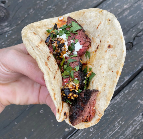 Hardcore Carnivore: Tex Mex seasoning, grilled steak taco with chopped herbs and spicy condiment in a soft tortilla.