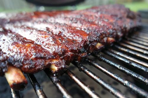 Hardcore Carnivore - Red Seasoning, close-up of a glazed, flavorful barbecued rack of ribs on a grill.