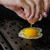 GrillGrate® for The Original & PK300 Grill, close-up of a person cracking an egg on a grill grate.