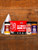 HowToBBQRight Ultimate Bird Brine Kit, red turkey brine kit box with bird brine, Killer Hogs AP seasoning, King Craw Cajun seasoning, and a brining bag displayed on a wooden shelf.