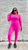 Black female model with sleek black bob wearing MTAP buttery soft hot pink long sleeve top and matching high-waisted leggings with white sneakers against a pink background.