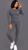 Black female model with sleek black bob wearing MTAP buttery soft charcoal long sleeve top and matching high-waisted leggings with white sneakers against a gray background.