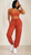 Black female model with sleek bob hairstyle wearing rust orange high-waisted jogger pants with matching lace bralette from MTAP Boutique