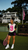 Black woman wearing Legacy Club oversized jersey with biker shorts and white sneakers at a luxury country club.