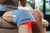 Person using Novaa Lab red light therapy knee wrap on knee while seated for targeted joint and muscle recovery support