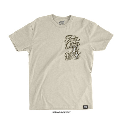 Natural bone signature lightweight tee, front. Airbrushed left-chest design reading "Tracy Cortez / Born For This" in sepia-toned script with two cherub angels. Born For This™ neck logo and side label.