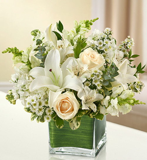 Elegant white flowers help to convey your deepest sympathies with graceful beauty that heals the soul. Our lovely cube vase arrangement offers a lasting tribute to friends and family members, crafted from fresh roses, lilies, snapdragons, monte casino and more.