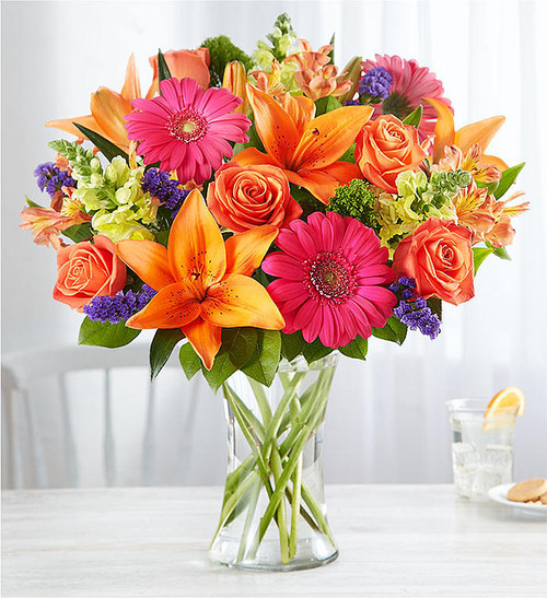 Putting a bright start in somebody's day starts with a beautiful gift. Our delightfully vibrant bouquet is filled with a medley of blooms in cheerful pops of orange, pink and yellow, with plenty of lush greenery mixed in.