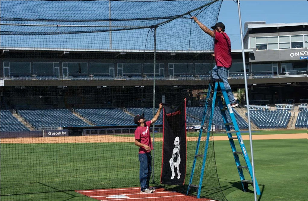 Cimarron Sports installation crew securing batting cage netting at a baseball stadium