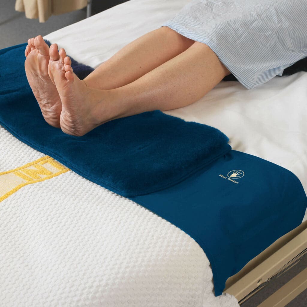 Heels resting on a soft Merino wool Pressure Care Assistant pad at the foot of the bed