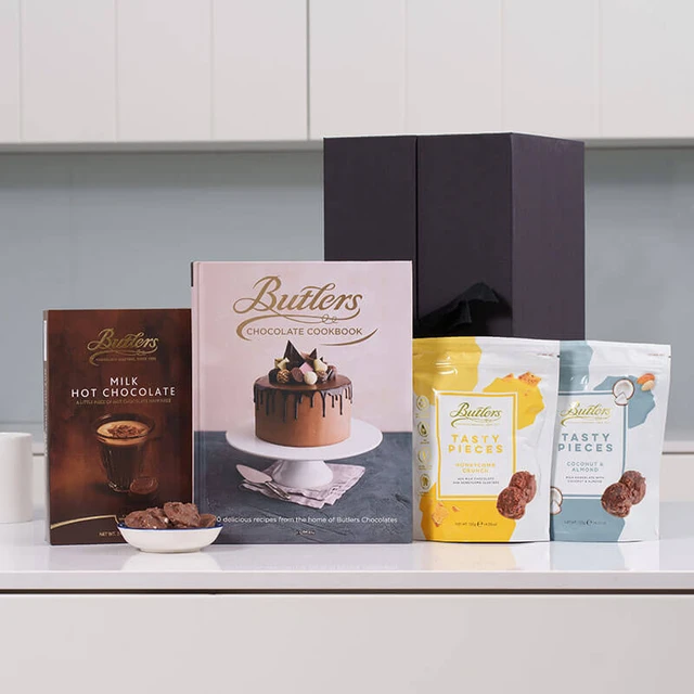 Butlers Chocolate Lovers Gift Set featuring Milk Hot Chocolate box, Chocolate Cookbook, and two Tasty Pieces bags in yellow and blue packaging – indulgent treat for chocolate enthusiasts.