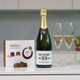 Happy 70th Birthday gift set featuring personalised champagne bottle with celebratory label, Lily O'Brien's Sticky Toffee chocolates, and two filled champagne glasses. Happy 70th Birthday gift set featuring personalised champagne bottle with celebratory label, Lily O'Brien's Sticky Toffee chocolates, and two filled champagne glasses.