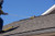 Worker on a shingle roof using a Ridge Pro anchor to safely access the roof.