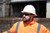Worker wearing Malta Dynamics tinted safety glasses with a hard hat outdoors