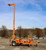 Malta X1000E road-towable electric mobile grabber deployed on a jobsite with the mast fully extended to an overhead anchor point