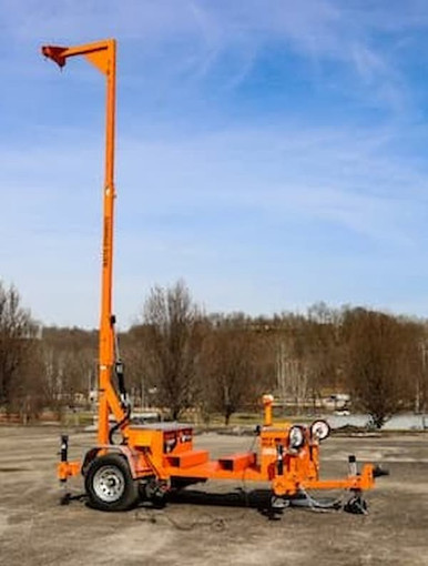 Malta X1000 road-towable mobile grabber with the manual-hydraulic mast fully extended to a 22 ft overhead anchor against a blue sky