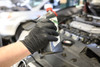 6016B_ - 6016BL - 21578 - Worker wearing 6 mil black nitrile disposable gloves holding a bottle of oil