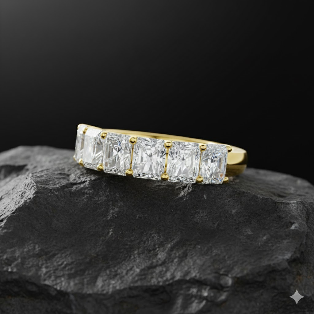 A top-down view of a 14K yellow gold wide band ring with five horizontally-set emerald-cut diamonds atop rock.