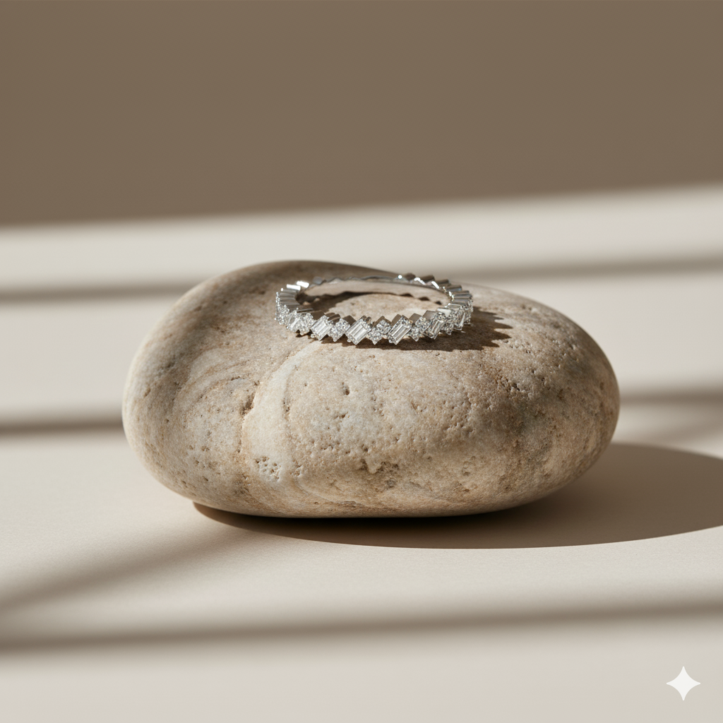 A close-up view of a 14K yellow gold band ring with an alternating pattern of baguette and round diamonds on a beige stone.