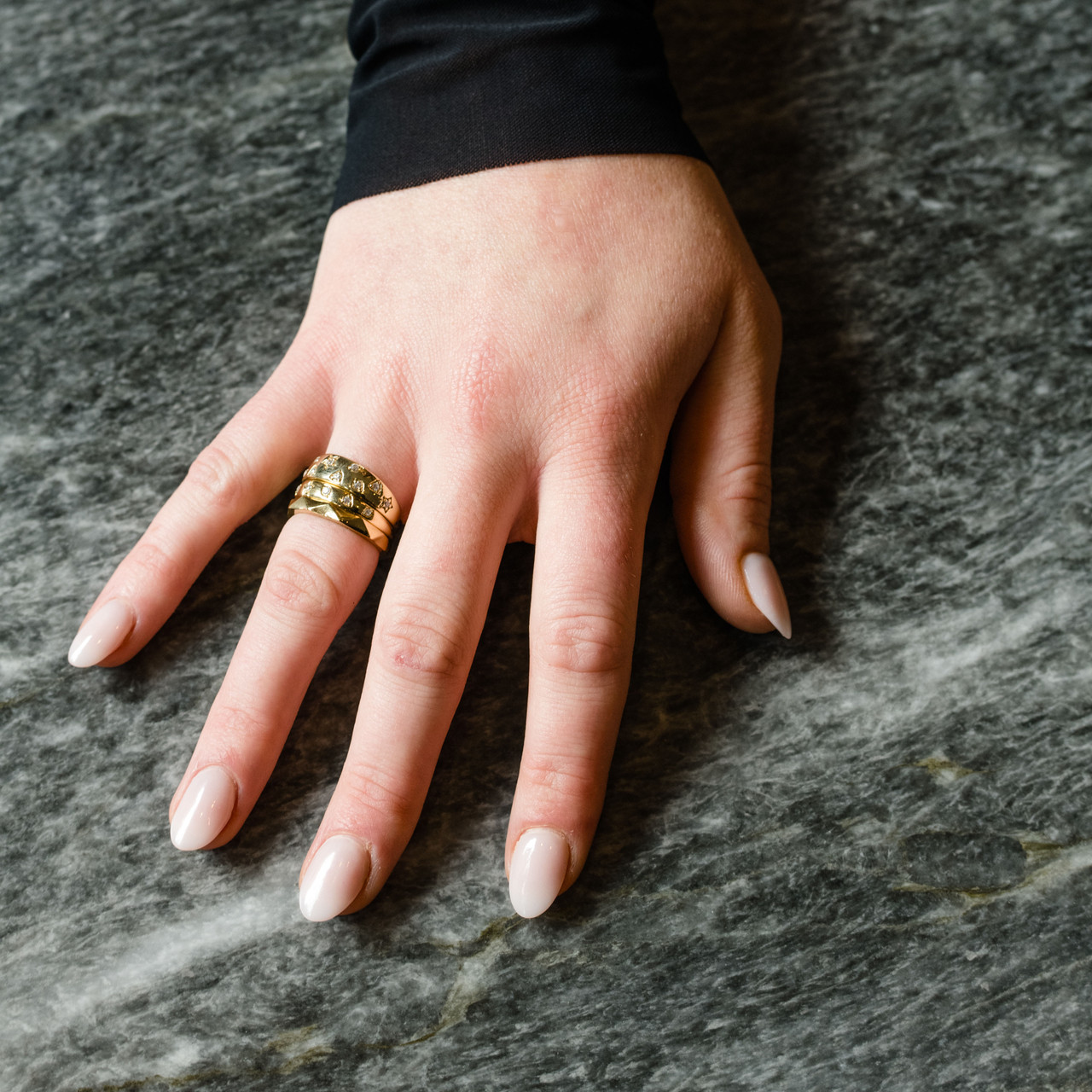 A lifestyle view of the Fourteenth Collection rose gold star studded diamond ring, highlighting sculpted star-shaped bezel settings and round diamonds embedded into a substantial, polished band.