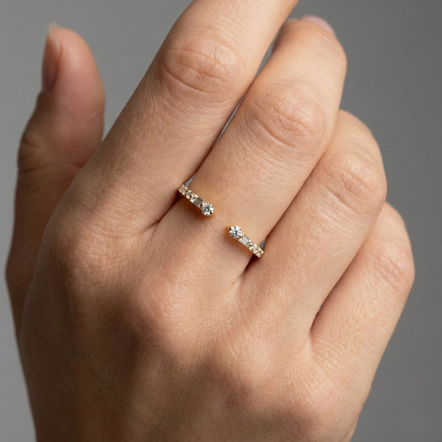 Amorati Diamonds Embrace Cluster Ring, a top-down view of a 10K yellow gold bypass ring with a three-diamond cluster at each end on hand.