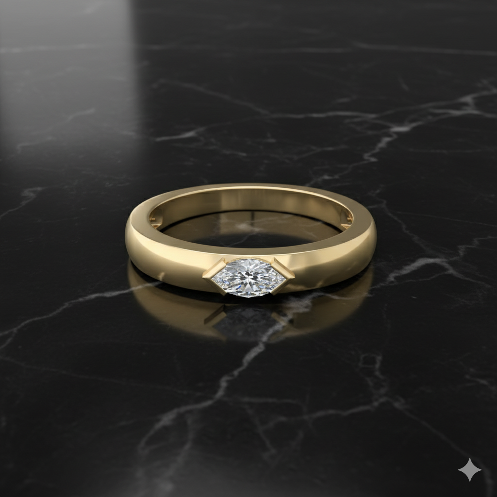 A top-down view of a 14K yellow gold bypass ring with a single, bezel-set round diamond in a fluid, curving band on marble